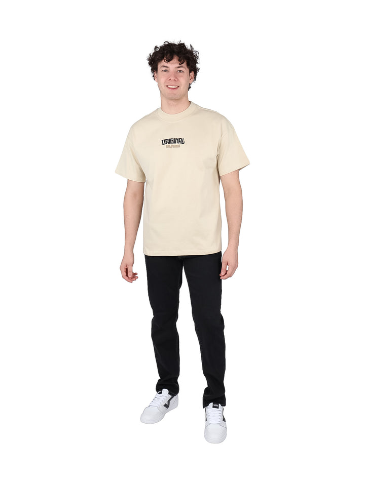 Hombre vistiendo playera oversize color beige con estampado negro en el pecho.
