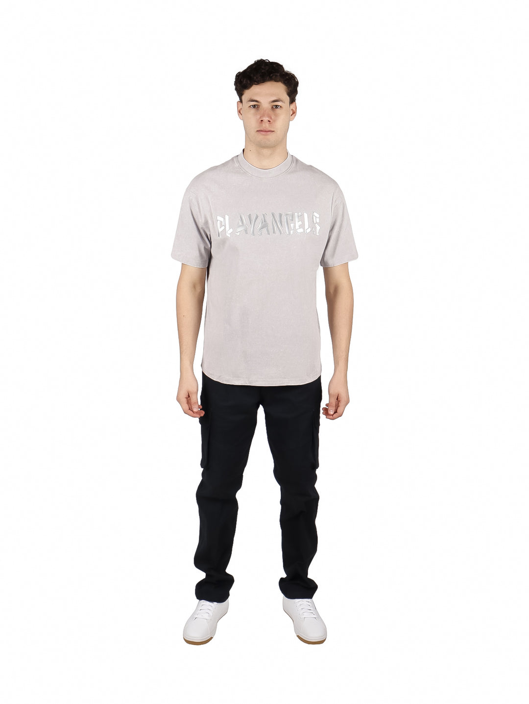 Hombre vistiendo playera oversize color gris con letras blancas en el pecho y cuello redondo.