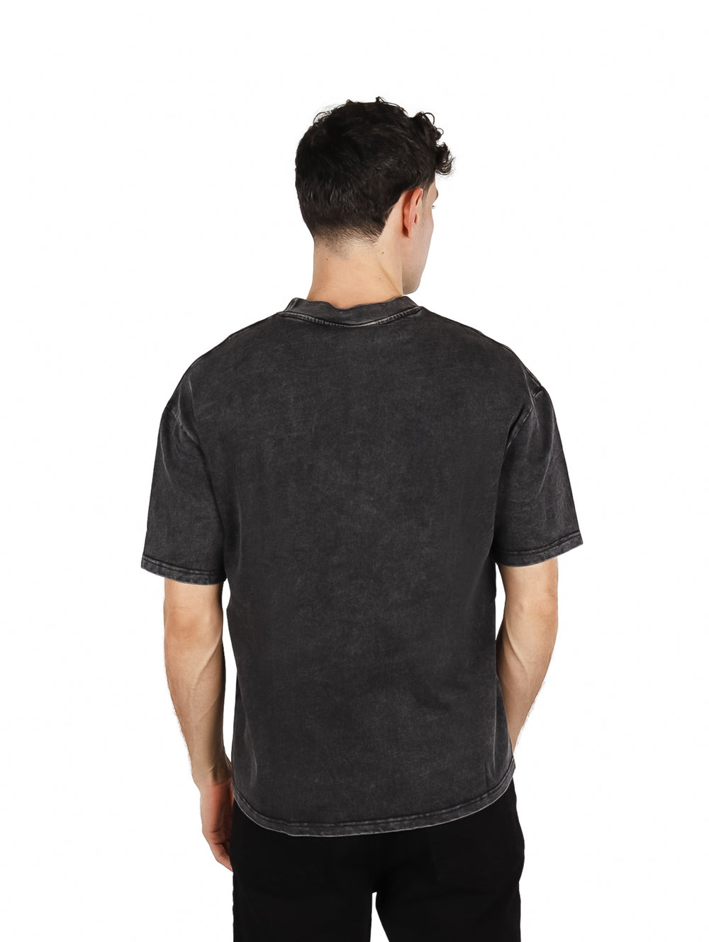 Hombre vistiendo playera oversize color negro con estampado frontal blanco.