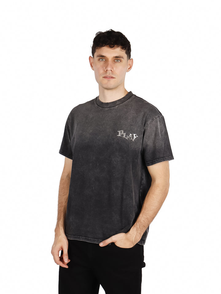 Hombre vistiendo playera oversize color negro con efecto lavado y texto &