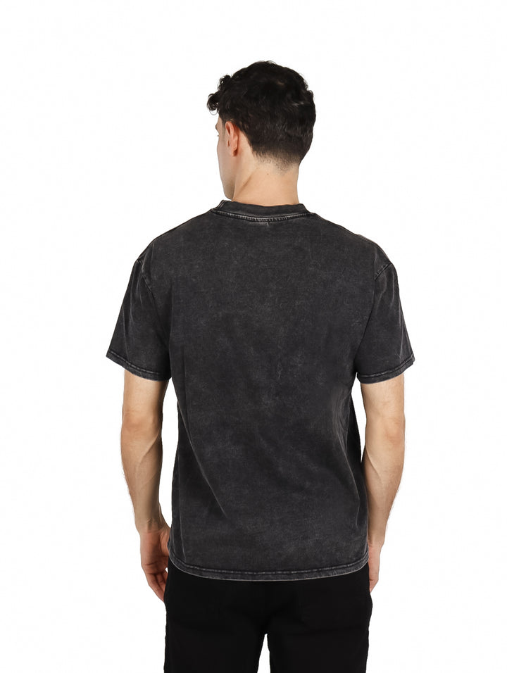Hombre vistiendo playera oversize color negro con efecto lavado y texto &