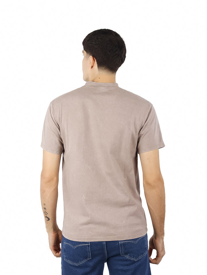 Hombre vistiendo playera oversize de color café con cuello redondo y manga corta.