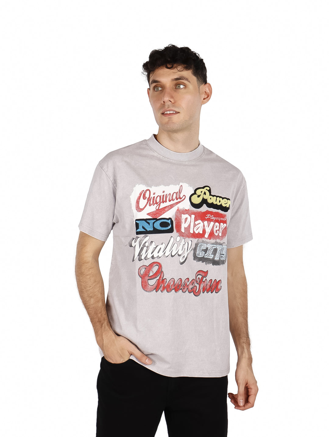 Hombre vistiendo playera oversize gris claro con estampado de letras multicolores en el pecho.