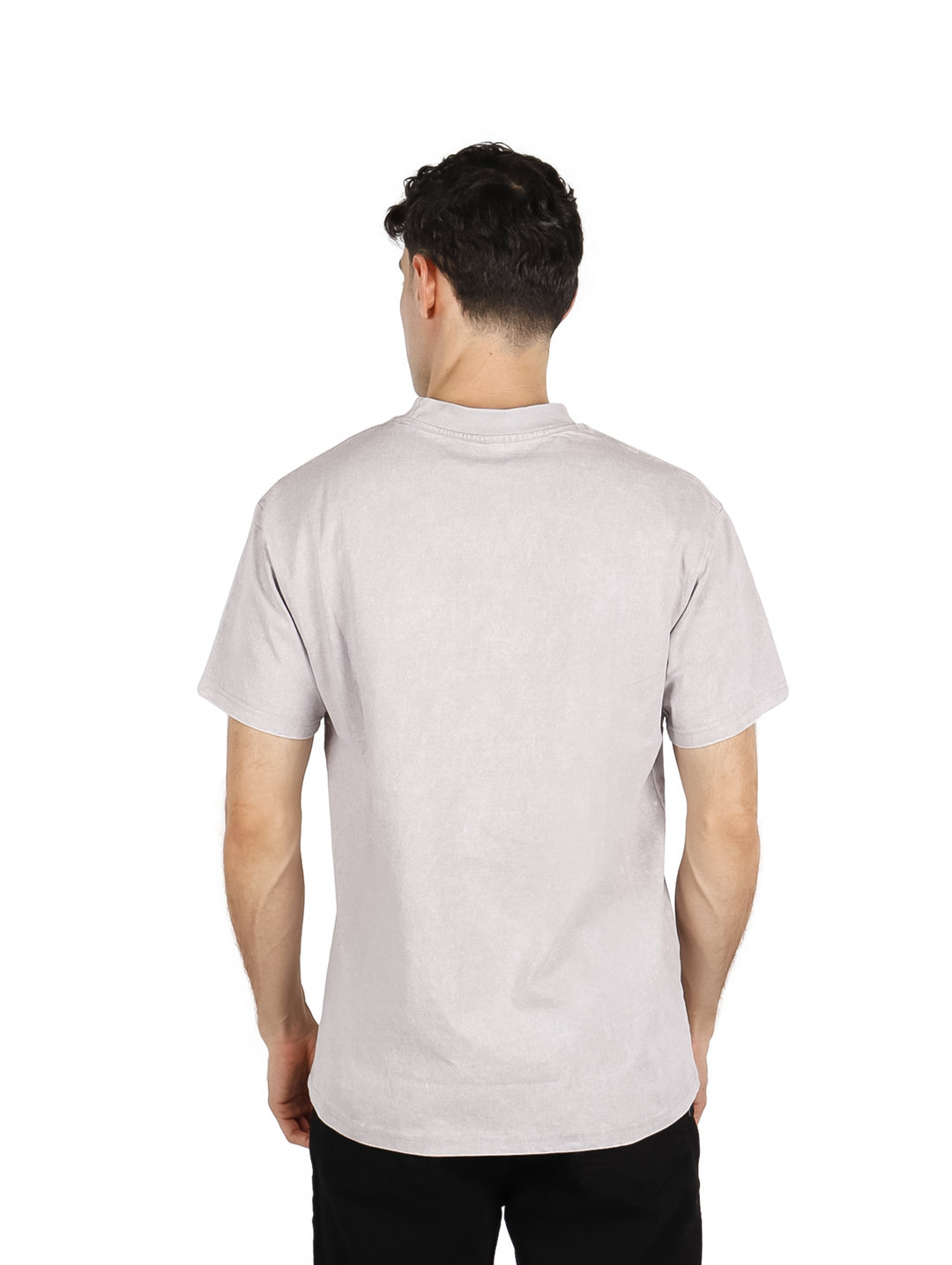 Hombre vistiendo playera oversize gris claro con estampado de letras multicolores en el pecho.