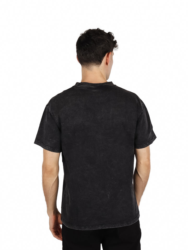 Hombre vistiendo playera oversize color negro con estampado colorido en el pecho.