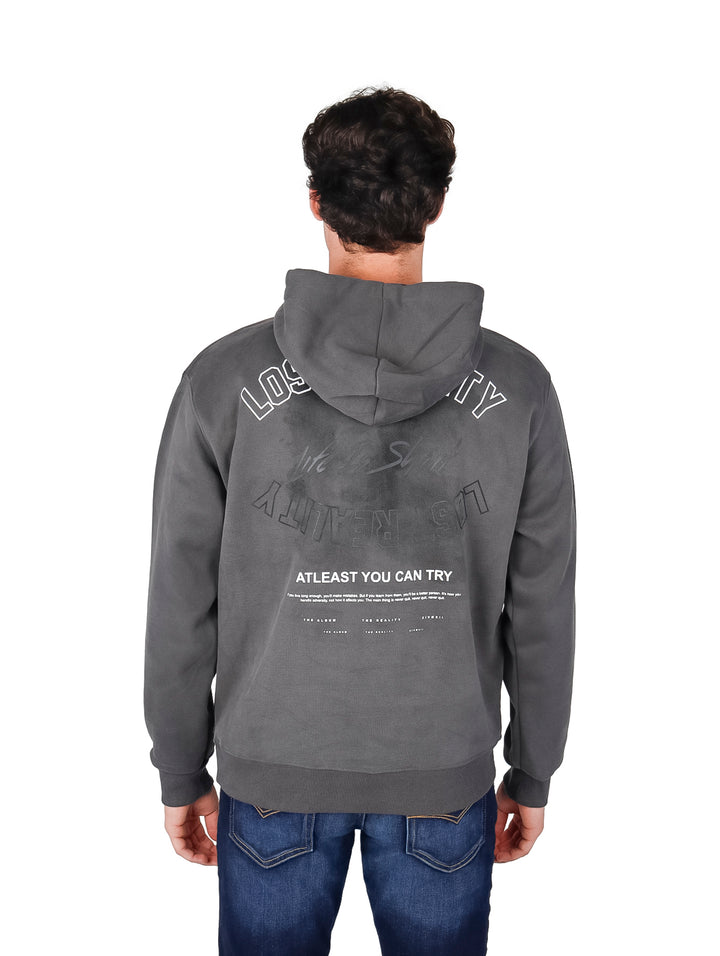 Hombre usando sudadera con capucha color gris oscuro con estampado blanco y cordones blancos.