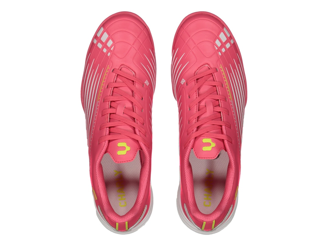 Zapato de fútbol Charly color rosa con detalles blancos y suela para césped sintético.