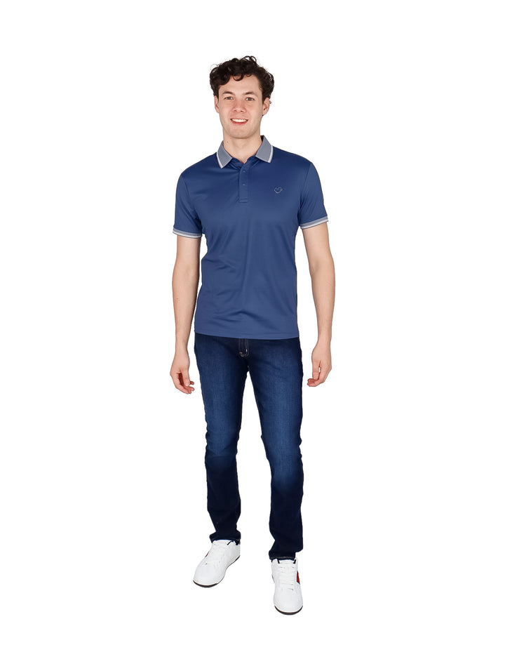 Hombre vistiendo playera polo color azul marino con detalles en gris en el cuello y mangas.