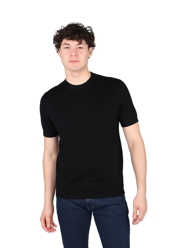 Hombre vistiendo una playera negra de manga corta y cuello redondo.