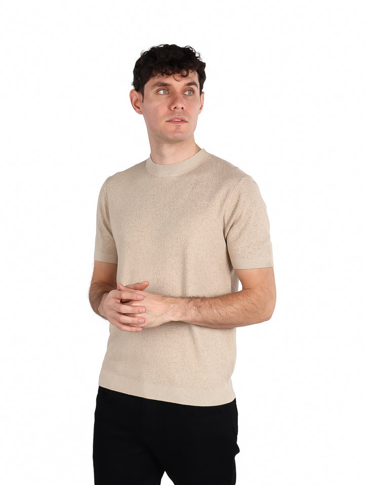 Hombre vistiendo una playera de manga corta color beige con cuello redondo y textura gruesa.