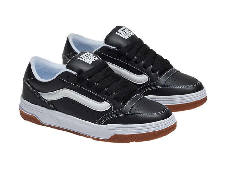 Tenis Vans Hylane en color negro con franja blanca y suela de goma marrón sobre fondo blanco.