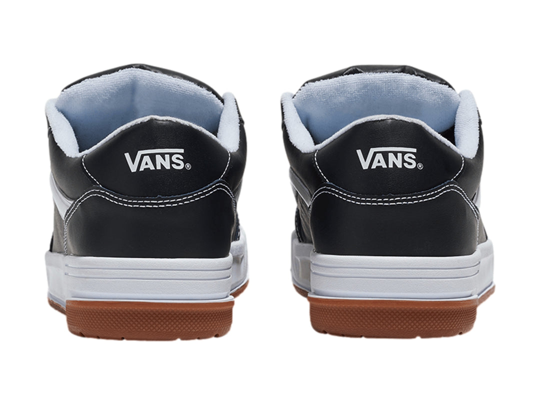 Tenis Vans Hylane en color negro con franja blanca y suela de goma marrón sobre fondo blanco.
