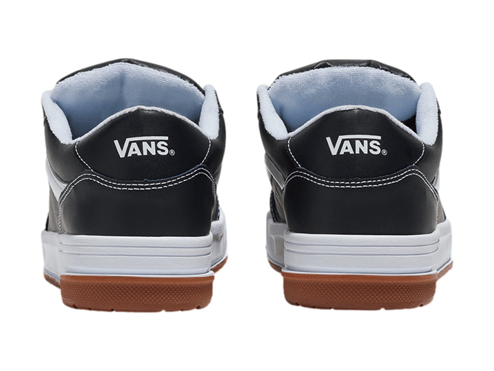 Tenis Vans Hylane en color negro con franja blanca y suela de goma marrón sobre fondo blanco.