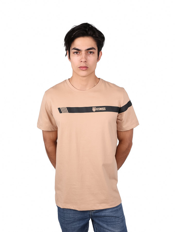 Hombre vistiendo playera beige de manga corta con franja negra horizontal y logo de K-SWISS en el pecho.