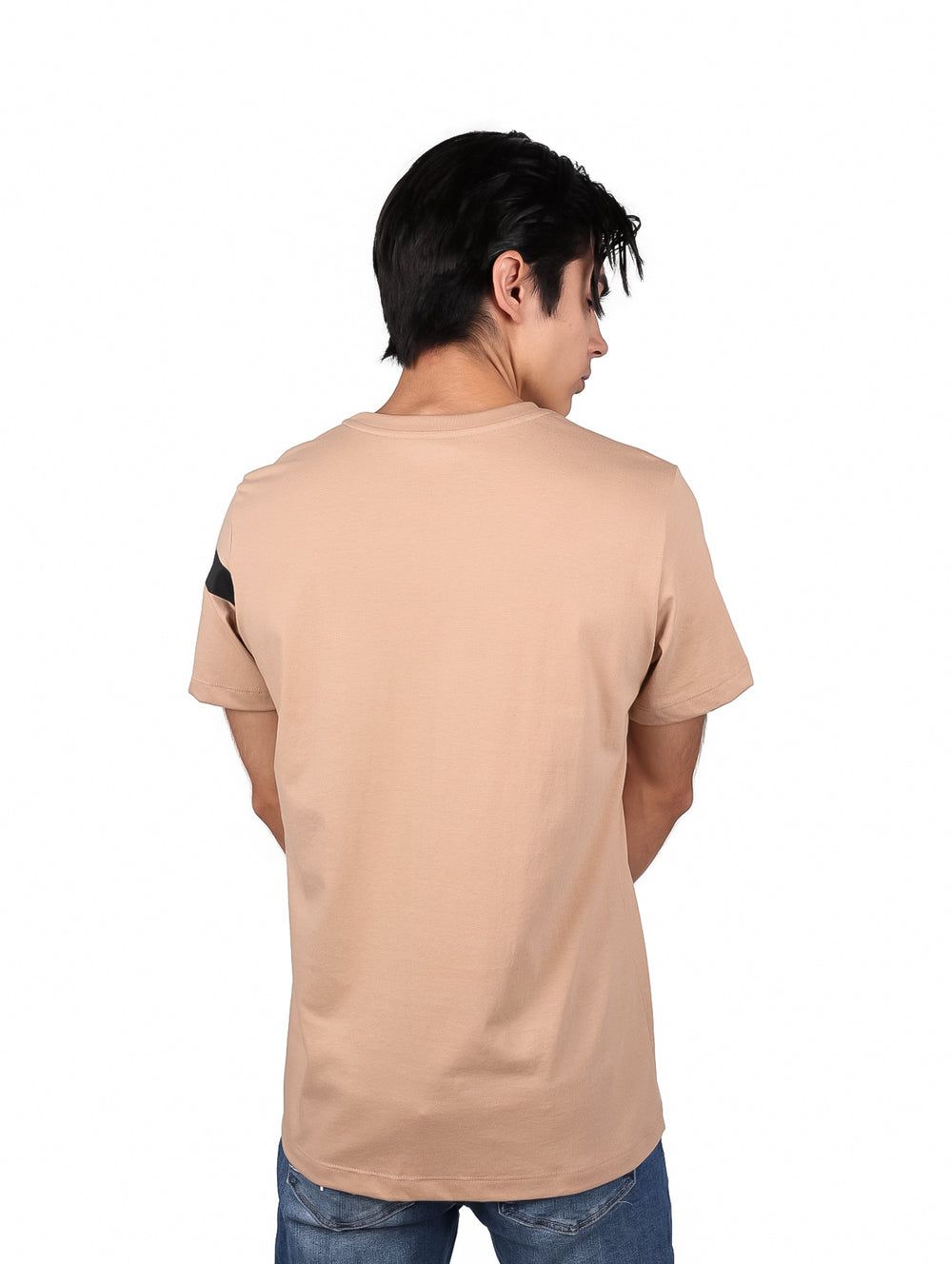 Hombre vistiendo playera beige de manga corta con franja negra horizontal y logo de K-SWISS en el pecho.