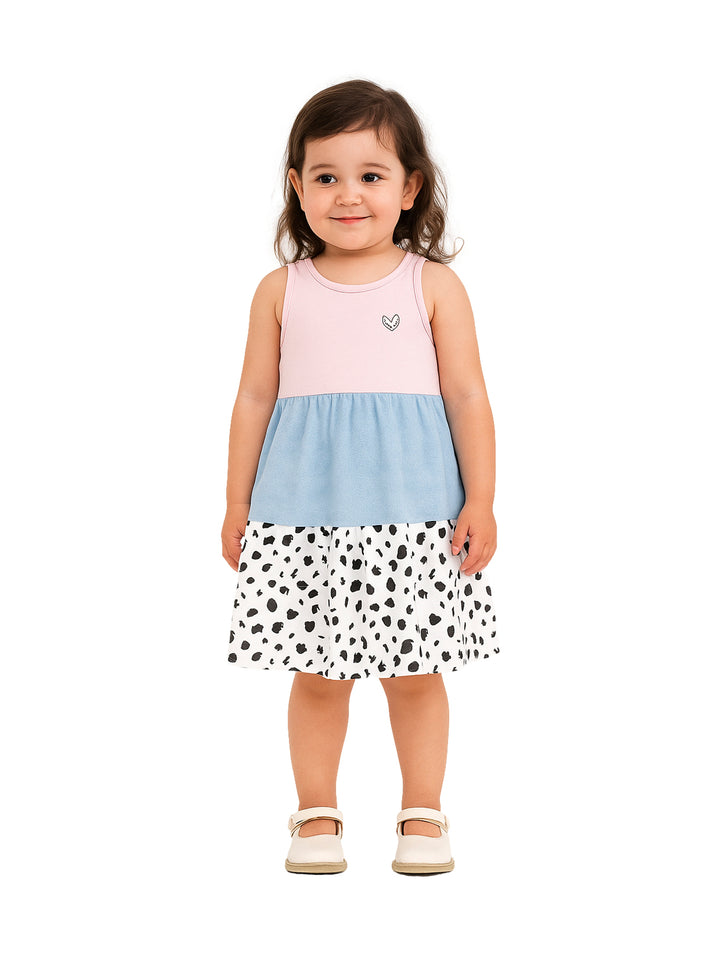 Niña pequeña vistiendo un vestido tricolor en rosa, azul y blanco con puntos negros.
