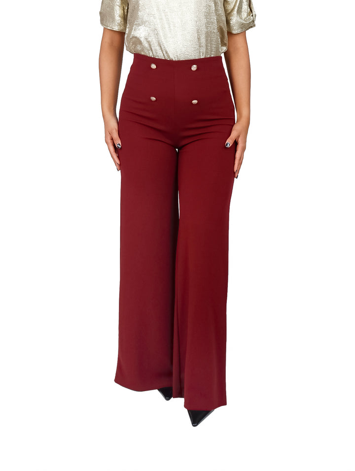 Pantalón amplio de color vino con botones decorativos en la cintura.