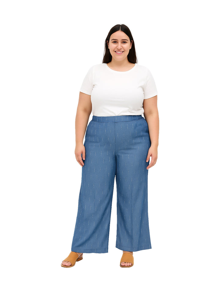 Mujer vistiendo pantalón azul de pierna ancha con rayas verticales blancas y camiseta blanca.