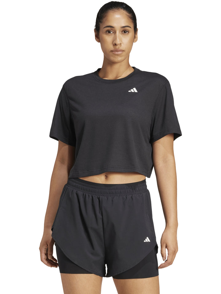 Mujer vistiendo conjunto deportivo Adidas color negro compuesto por camiseta corta y shorts.