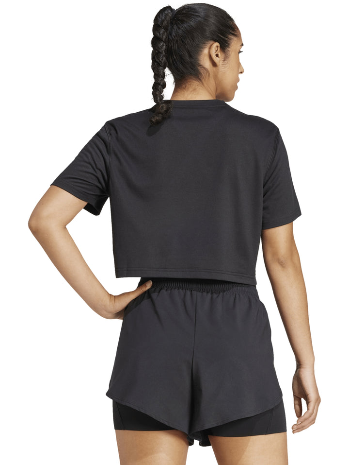 Mujer vistiendo conjunto deportivo Adidas color negro compuesto por camiseta corta y shorts.