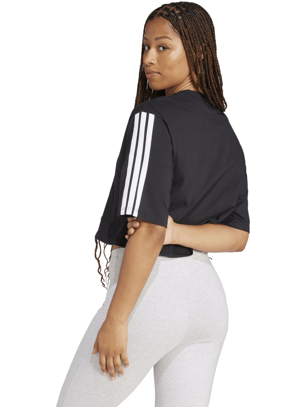 Mujer vistiendo playera holgada negra de algodón Adidas con rayas blancas en las mangas.