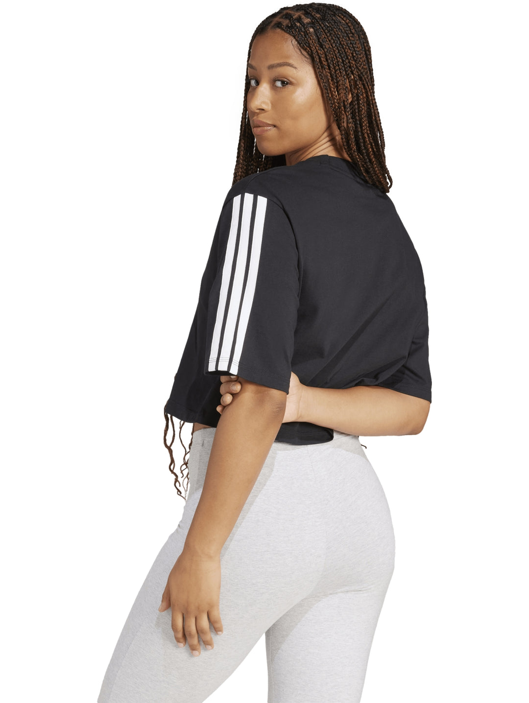 Mujer vistiendo playera holgada negra de algodón Adidas con rayas blancas en las mangas.