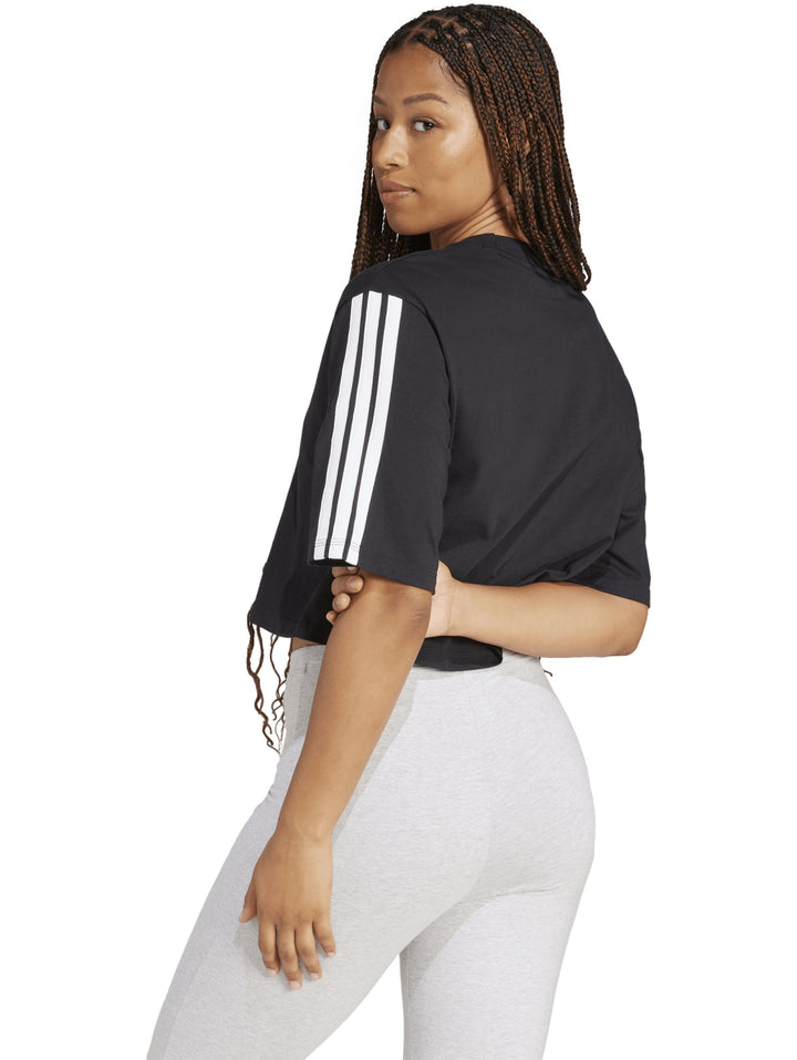 Mujer vistiendo playera holgada negra de algodón Adidas con rayas blancas en las mangas.