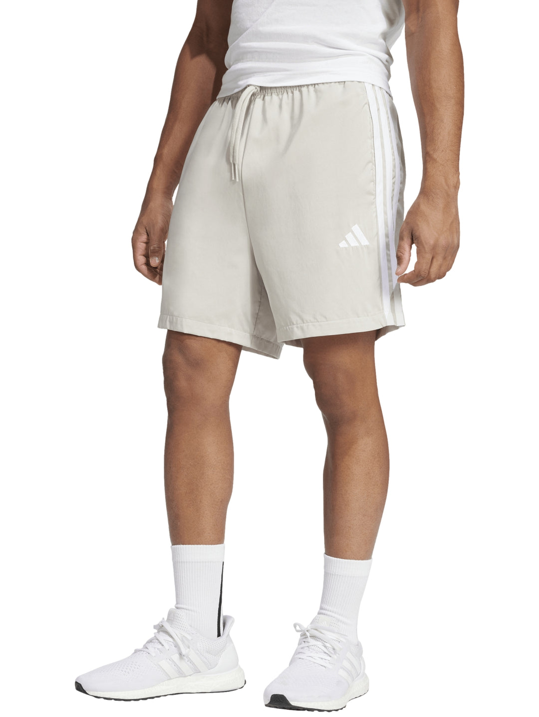 Shorts deportivos Adidas color beige con tres rayas blancas laterales y logo frontal.