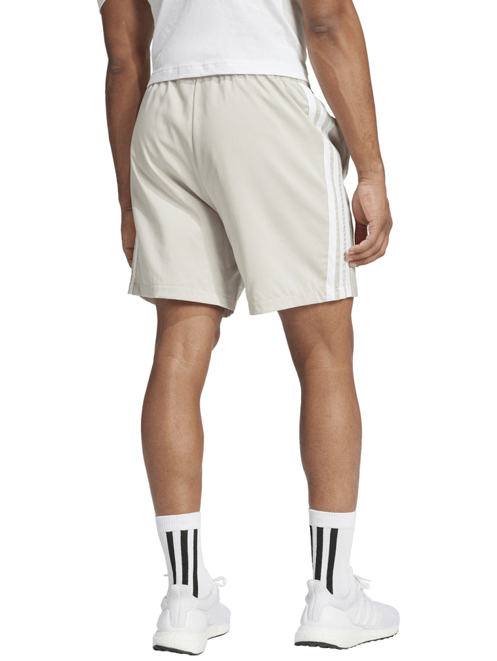 Shorts deportivos Adidas color beige con tres rayas blancas laterales y logo frontal.