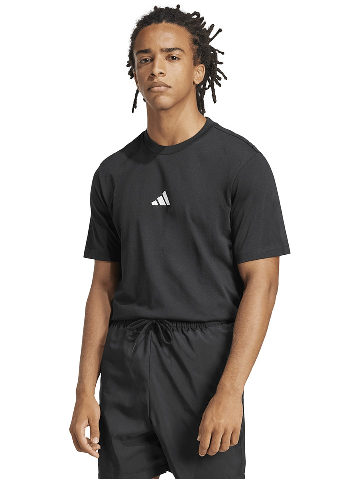 Hombre vistiendo playera negra de manga corta con logo pequeño de Adidas en el pecho.