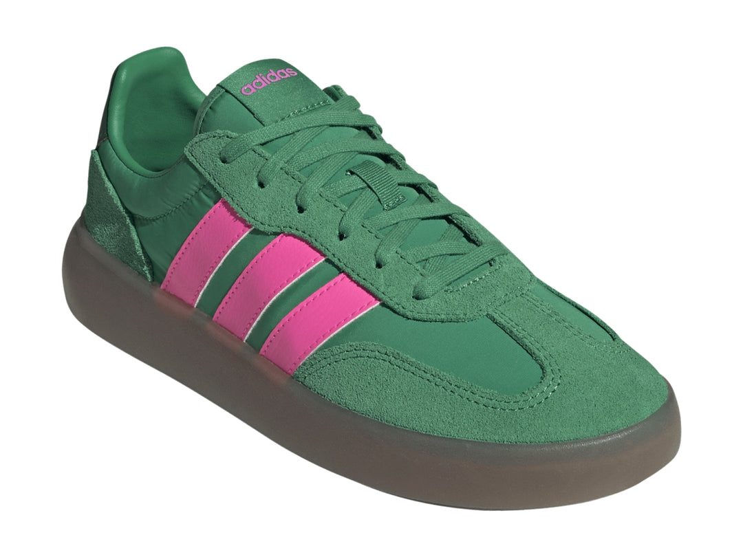 Tenis Adidas color verde con tres franjas rosas laterales y suela gris oscuro.