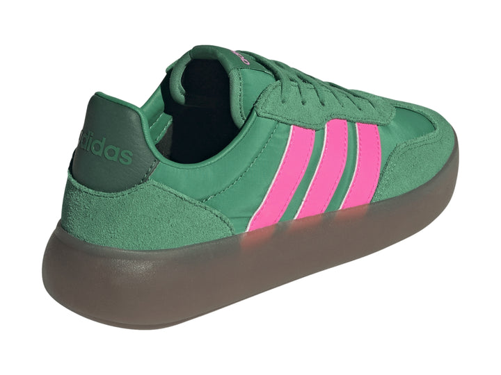 Tenis Adidas color verde con tres franjas rosas laterales y suela gris oscuro.