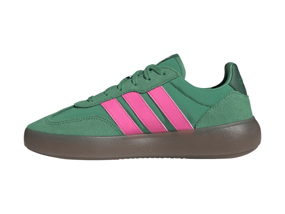 Tenis Adidas color verde con tres franjas rosas laterales y suela gris oscuro.