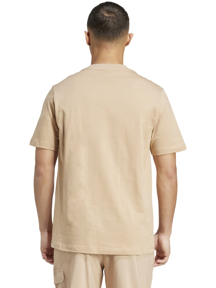 Hombre vistiendo playera Adidas color arena con logo negro en el pecho.
