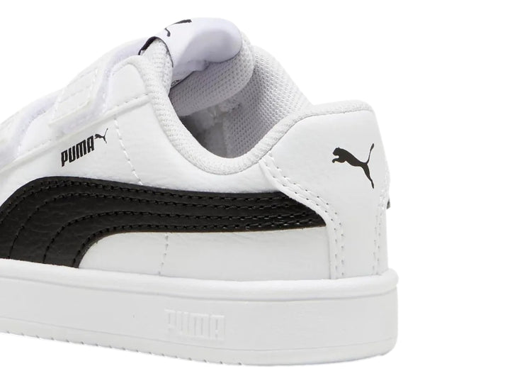 Tenis PUMA blancos para niño con franja negra lateral y cierre de velcro.