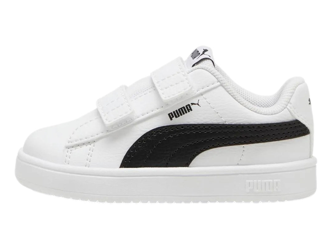 Tenis PUMA blancos para niño con franja negra lateral y cierre de velcro.