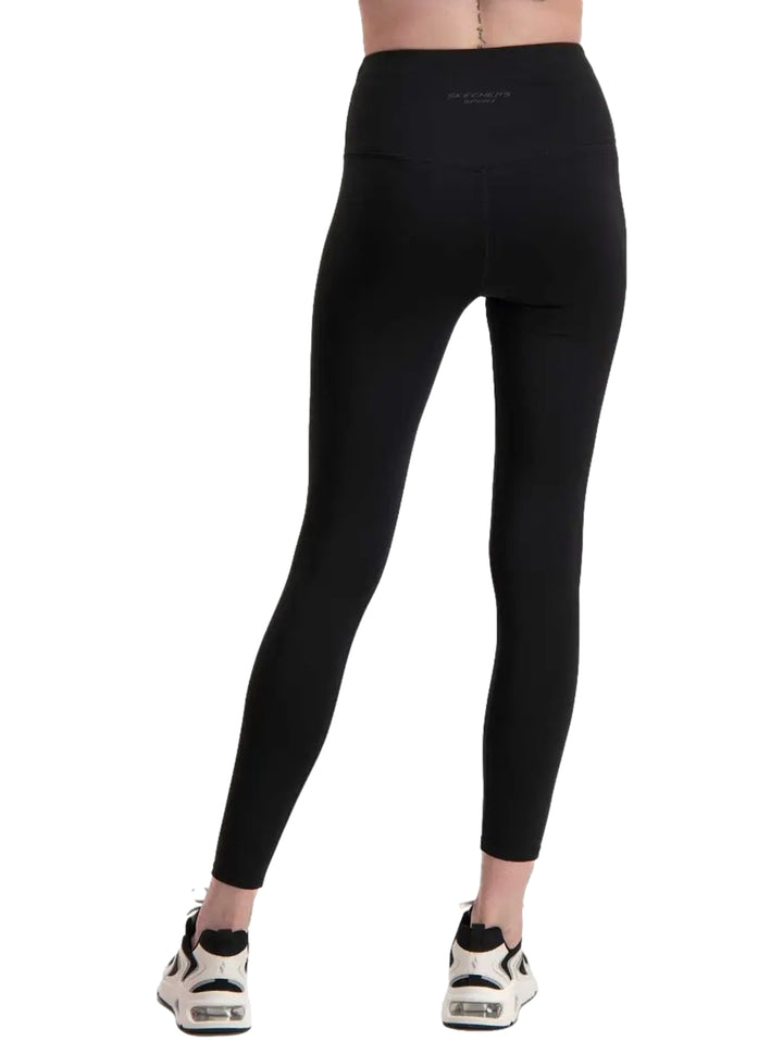 Mujer vistiendo leggings deportivos de color negro marca Skechers, ajustados al cuerpo y de talle alto.