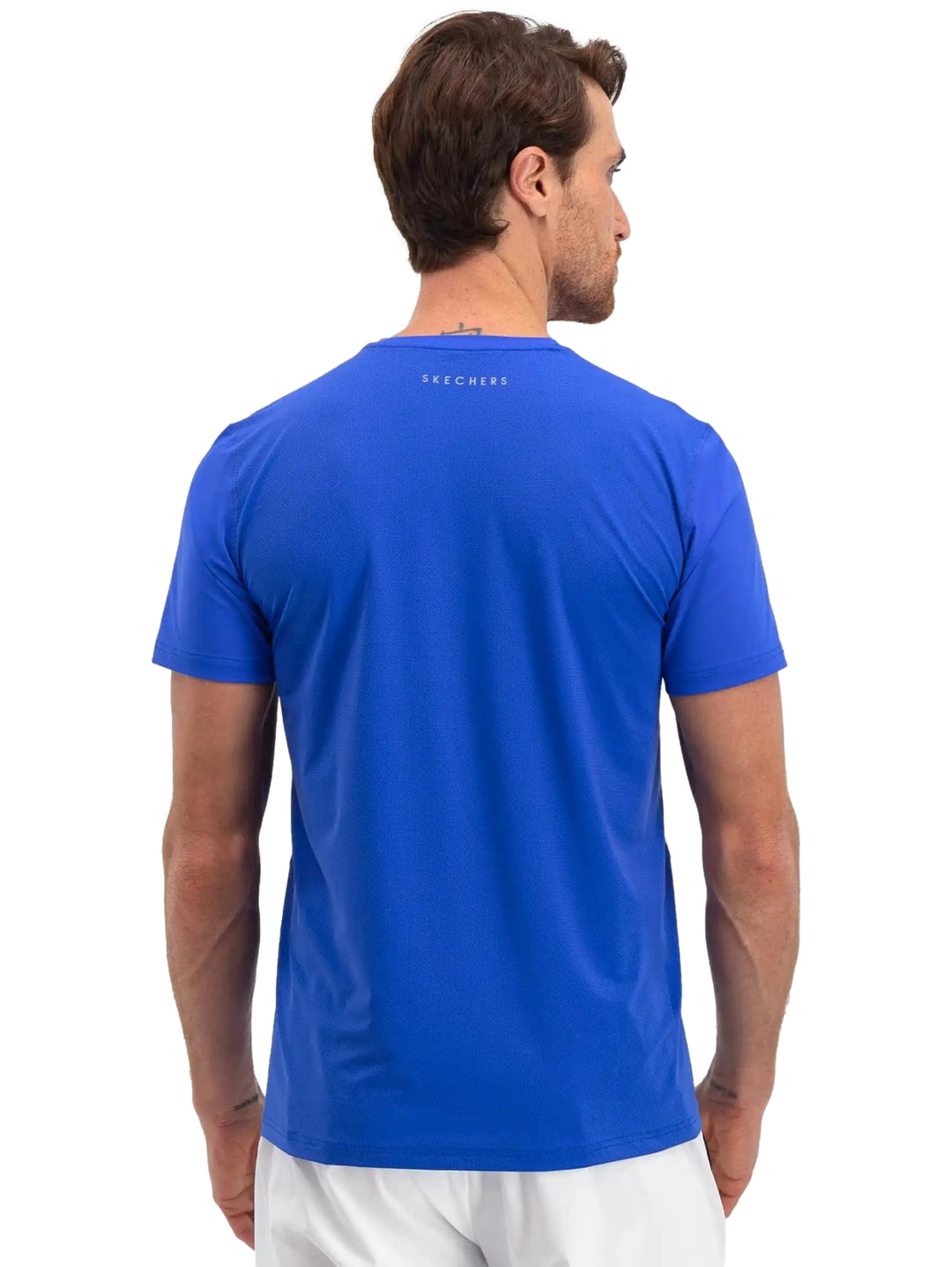 Hombre vistiendo una playera deportiva de color azul brillante de manga corta marca Skechers.