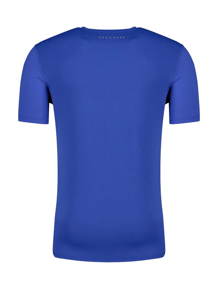 Hombre vistiendo una playera deportiva de color azul brillante de manga corta marca Skechers.