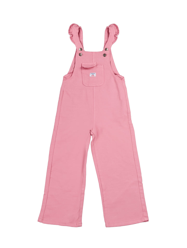 Niña vistiendo un overol color rosa de tirantes con camiseta blanca sobre fondo blanco.