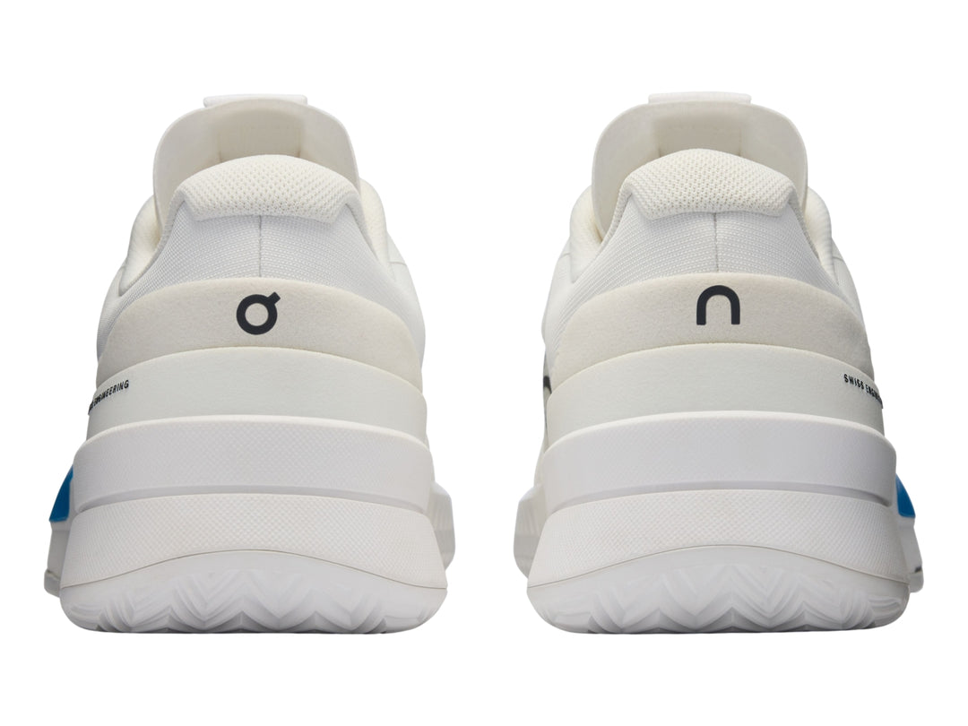 Tenis blancos On Cloud con detalle degradado en azul y rosa y logo negro en el lateral.