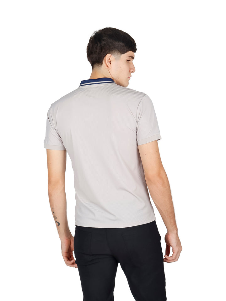 Hombre vistiendo playera polo color durazno con cuello azul marino y pantalones negros.