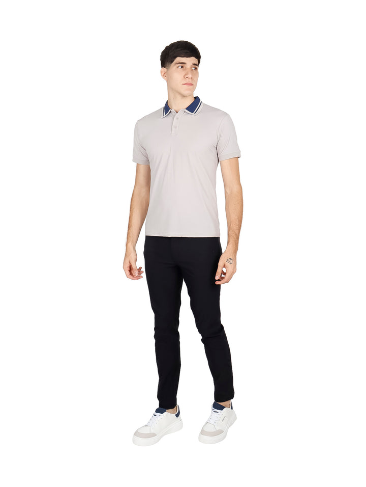 Hombre vistiendo playera polo color durazno con cuello azul marino y pantalones negros.