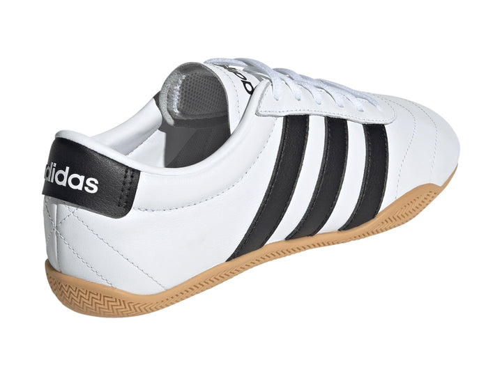 Tenis Adidas Grand Court Lo en color blanco con tres franjas negras y suela de goma color caramelo.