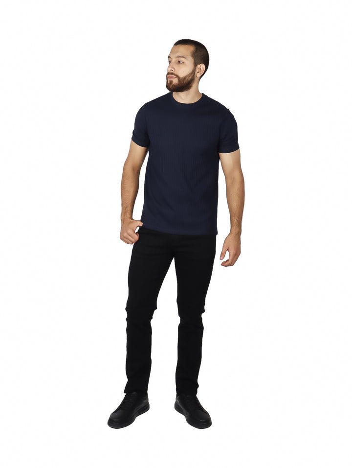 Hombre vistiendo camiseta de manga corta color azul oscuro con textura de rayas verticales.
