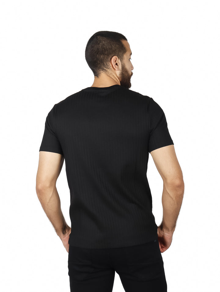 Hombre vistiendo una camiseta negra de manga corta con textura acanalada y cuello redondo.