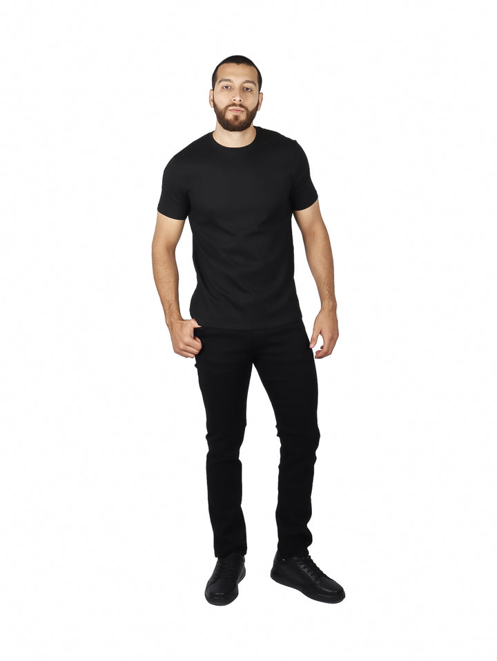 Hombre vistiendo una camiseta negra de manga corta con textura acanalada y cuello redondo.