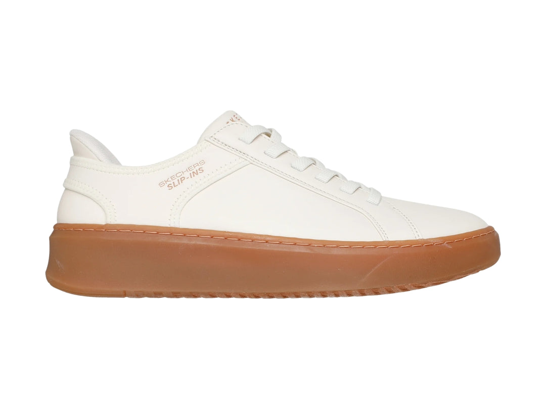 Tenis Skechers blancos con suela de goma color café y agujetas blancas.