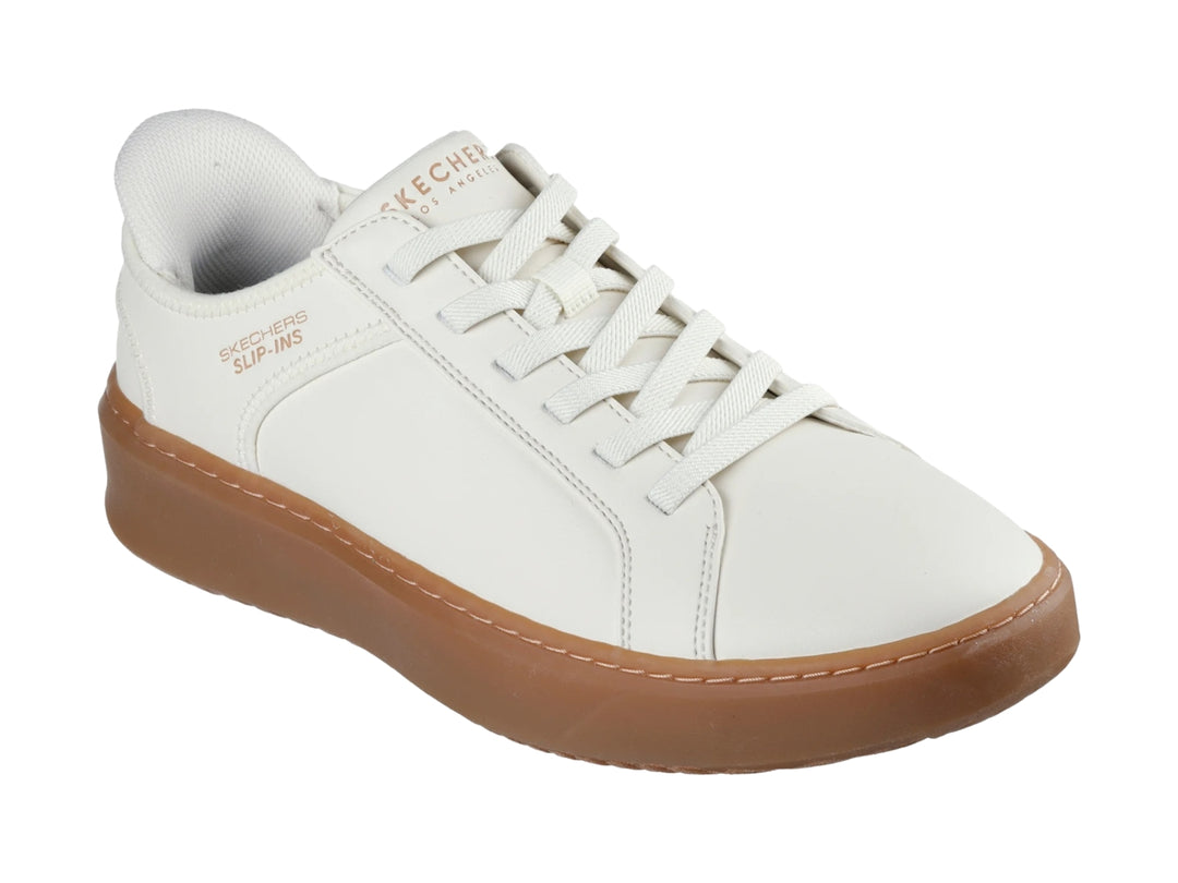 Tenis Skechers blancos con suela de goma color café y agujetas blancas.
