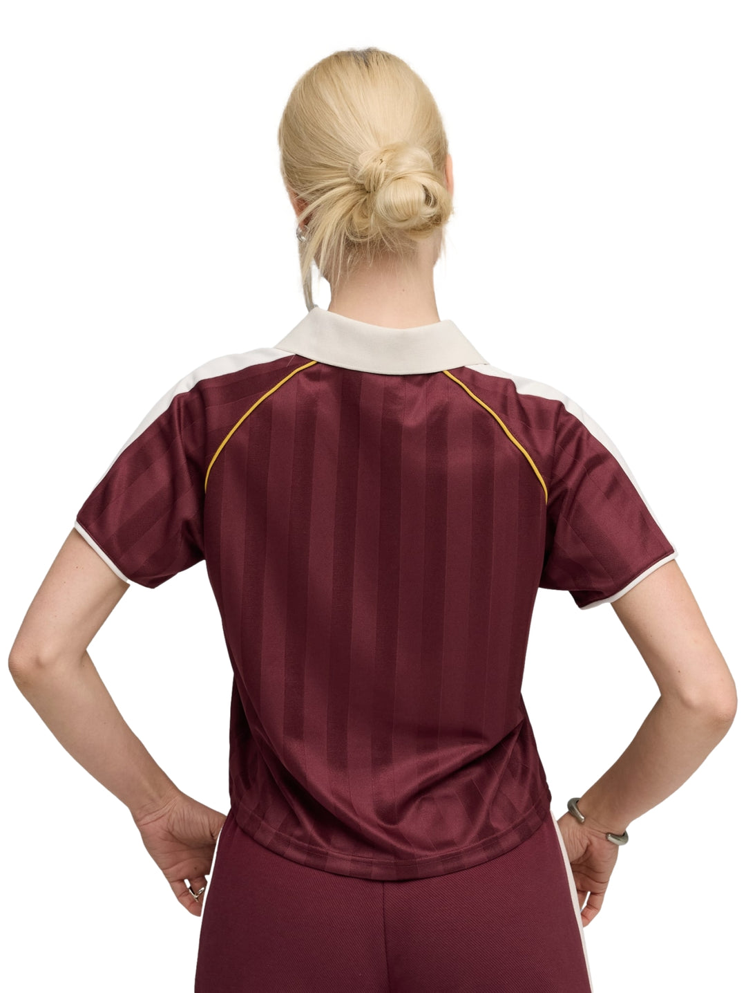 Mujer vistiendo playera y shorts deportivos PUMA en color ruby shimmer heather con detalles en blanco y dorado.